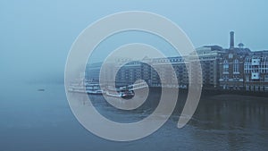 Butlers Wharf Pier and River Thames in thick fog and mist, on a cool blue morning in foggy and misty