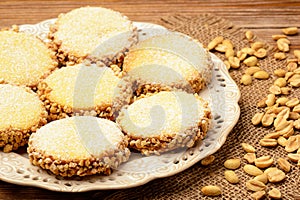 Butter cookies (alfajores) with caramel and peanuts on wooden background.