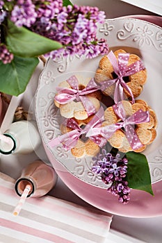 Butter cookies with pink ribbon,lilac flowers and chocolate milk