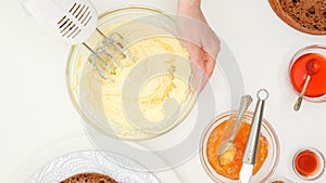 Butter cream, jam, syrup close up in bowls. Woman hands mixing cream using an electric mixer. Step by step chocolate cake recipe