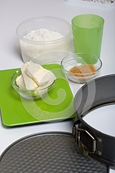 Butter on a kitchen scale. Sugar and flour in containers, collapsible baking dish. Levington cake, stages of preparation