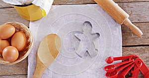 Butter paper, flour, rolling pin cookie cutter and eggs kept over a wooden table 4k