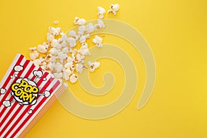 Butter popcorn in a red popcorn cup, snack in the house or cinema on a yellow background