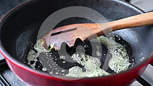 Butter and wooden spoon in hot iron frying pan. Close-up