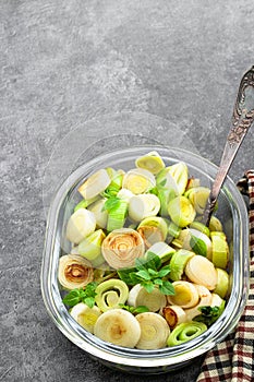 Buttered baked leek in glass bowl on gray background