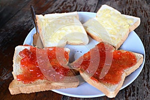 Buttered bread and strawberry jam on tableware