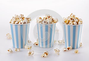 Buttered popcorn in striped paper cups over white background