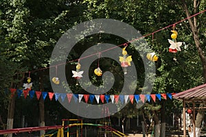 Butterflies and bees are made of plastic bottles hanging on a rope on a tree background