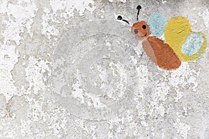 Butterfly painted by kids on a peeling wall aged by time