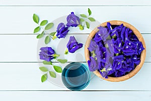 Butterfly pea or blue pea clitoria ternatea flowers and glass of blue ice tea isolated on wood table background.