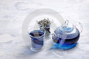 Butterfly pea flower tea is brewed in a glass teapot and served into a transparent cup. Blue herbal tea