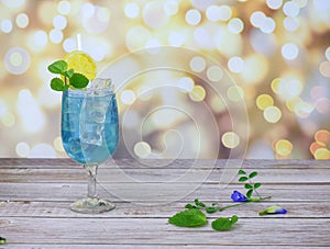 Butterfly pea flower water in a glass decorated with lemon slices on a wood table with blur backgroun