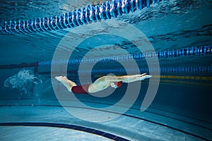 Butterfly swim style. Athletic young man, swimmer in motion training, preparing for competition, swimming in pool