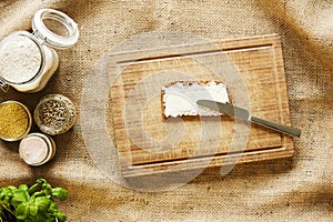 Buttering a slice of bread on wooden cutting board