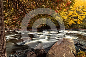 Buttermilk Falls in Long Lake, NY, Adirondacks, surrounded by vivid fall foliage on an overcast afternoon