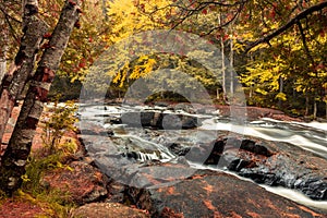 Buttermilk Falls in Long Lake, NY, Adirondacks, surrounded by vivid fall foliage on an overcast afternoon