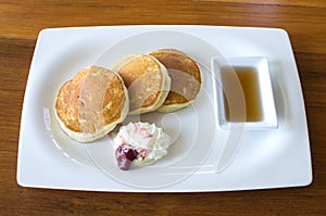 Buttermilk pancakes with maple syrup and weep cream in plate on