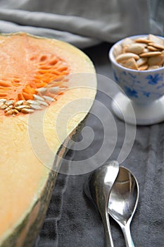Butternut squash sliced in half on a table with seeds in a cup. curcubitaceae photo