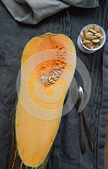 Butternut squash sliced in half on a table with seeds in a cup. curcubitaceae photo