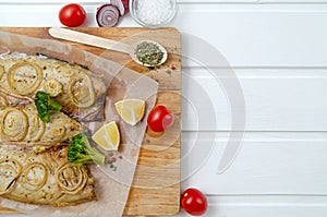 Buttery tasty fish mackerel saba with lemon, sliced on filet with tomatoes, onion rings herbs and broccoli in baking