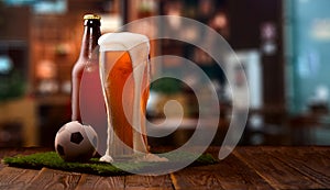 Buttle and glass of beer, soccer ball on green grass