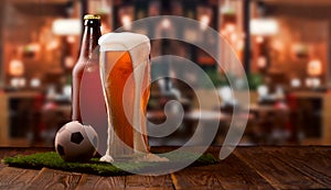 Buttle and glass of beer, soccer ball on green grass