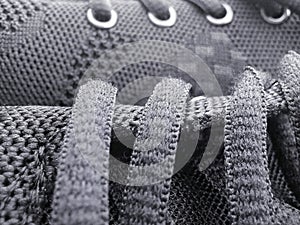 Buttonholes and laces of a gray shoe with a porous fabric texture