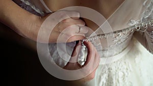 Buttoning bride wedding dress closeup. Hands fastening buttons on bridal white dress