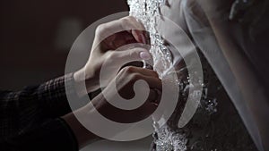 Buttoning bride wedding dress closeup. Hands fastening buttons on bridal white dress indoors