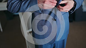 Buttoning a jacket. Stylish man in a suit fastening buttons on his jacket preparing to go out. Close up