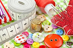 Buttons, colorful fabrics, measuring tape, pin cushion, thimble, spool of thread