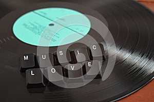 Buttons lettering music love on top of a black vinyl record