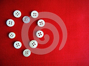 Buttons on red fabric background. Heart.