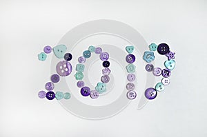 169/5000 Pugovitsy krasivo razlozheny na svetlom fone v forme 2019 Otkrytka s golubymi i fioletovymi pugovkami raznykh razmerov,