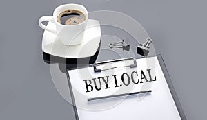 BUY LOCAL text on the paper sheet with coffee on the black background