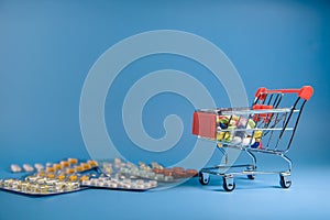 Buy medicine. Shopping basket with various medicinal, pills, tablets on blue background. Studio Photo