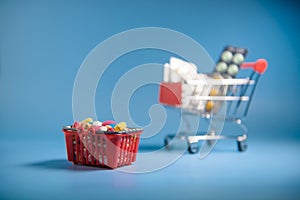 Buy medicine. Shopping basket with various medicinal, pills, tablets on blue background. Studio Photo