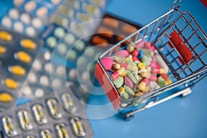 Buy medicine. Shopping basket with various medicinal, pills, tablets on blue background. Studio Photo