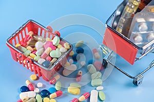 Buy medicine. Shopping basket with various medicinal, pills, tablets on blue background. Studio Photo