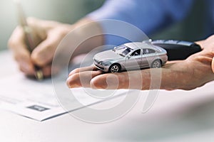 Buy new car concept - scale model and key in dealer hand