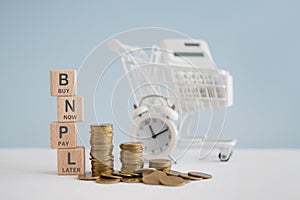 For buy now pay later , online shopping concept, wooden cube block with BNPL text and stack of coins, blurred white calculator in