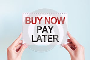 Buy now pay later word inscription on white card paper sheet in hands of a woman. Business concept