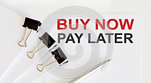 BUY NOW PAY LATER written on white page with office tools