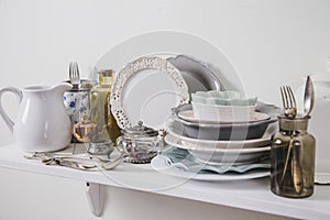Buy old vintage romantic tableware in secondhand store concept. Pile of valuable old tableware on store shelf for kitchen.