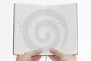 Buy / Sell choices on notepad, white background.