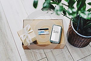 Buy sitting at home. Online shopping. Boxes, a smartphone and a plastic credit card to pay for the goods received