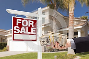 Buyer Handing Over Cash for House with For Sale Sign