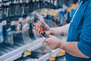 The buyer in the hardware store selects the goods. A man holds a wrench in his hand