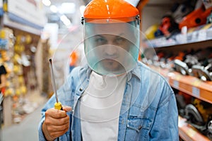 Buyer in mask holds screwdriver, hardware store