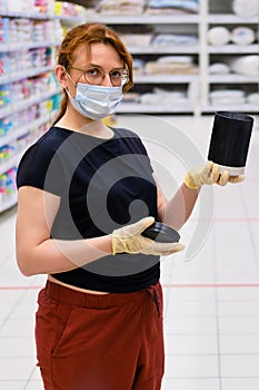 A buyer in a medical mask chooses products in a supermarket. Sale of household goods in the store